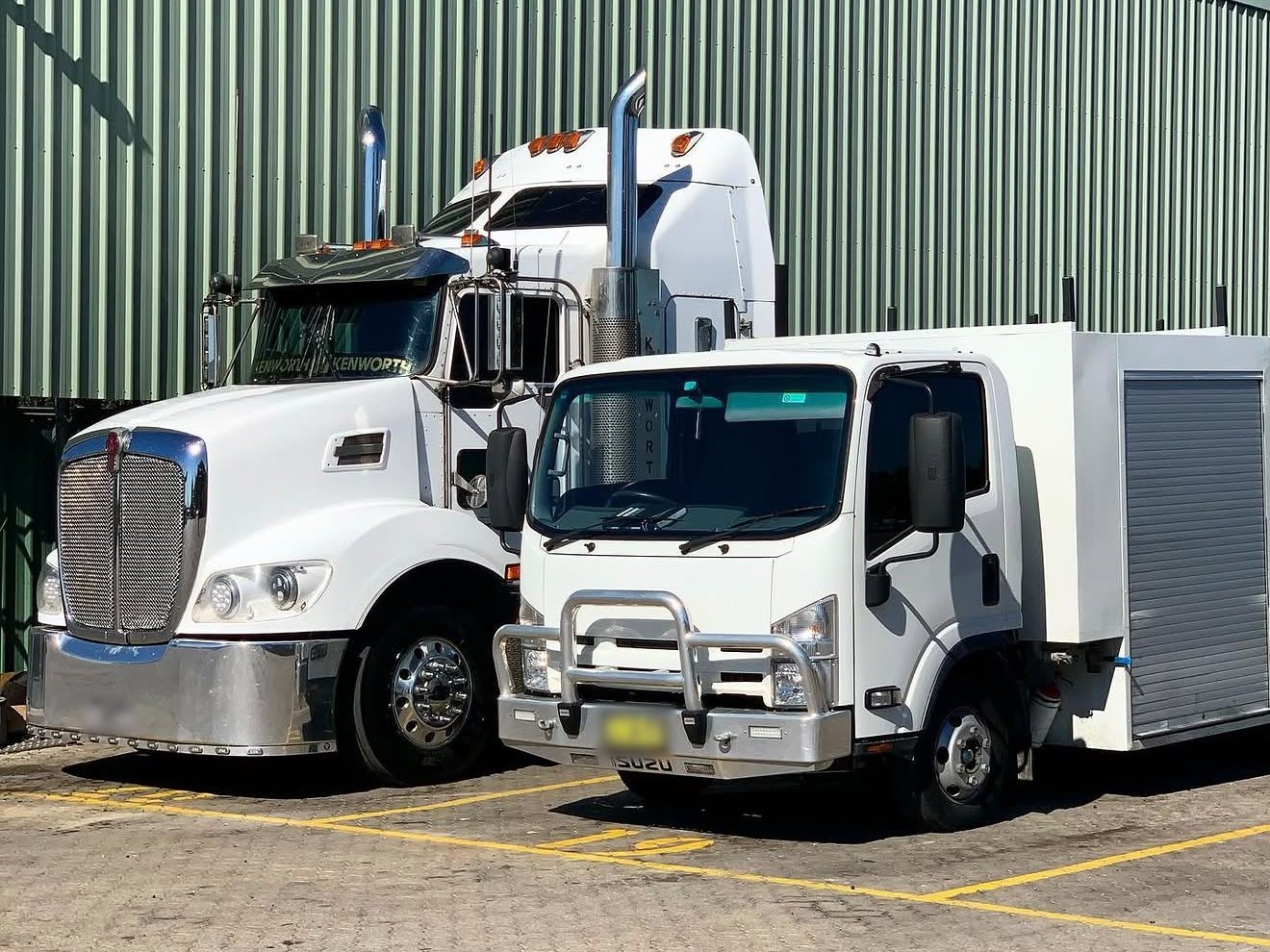Kenworth prime mover and Isuzu truck parked in a depot