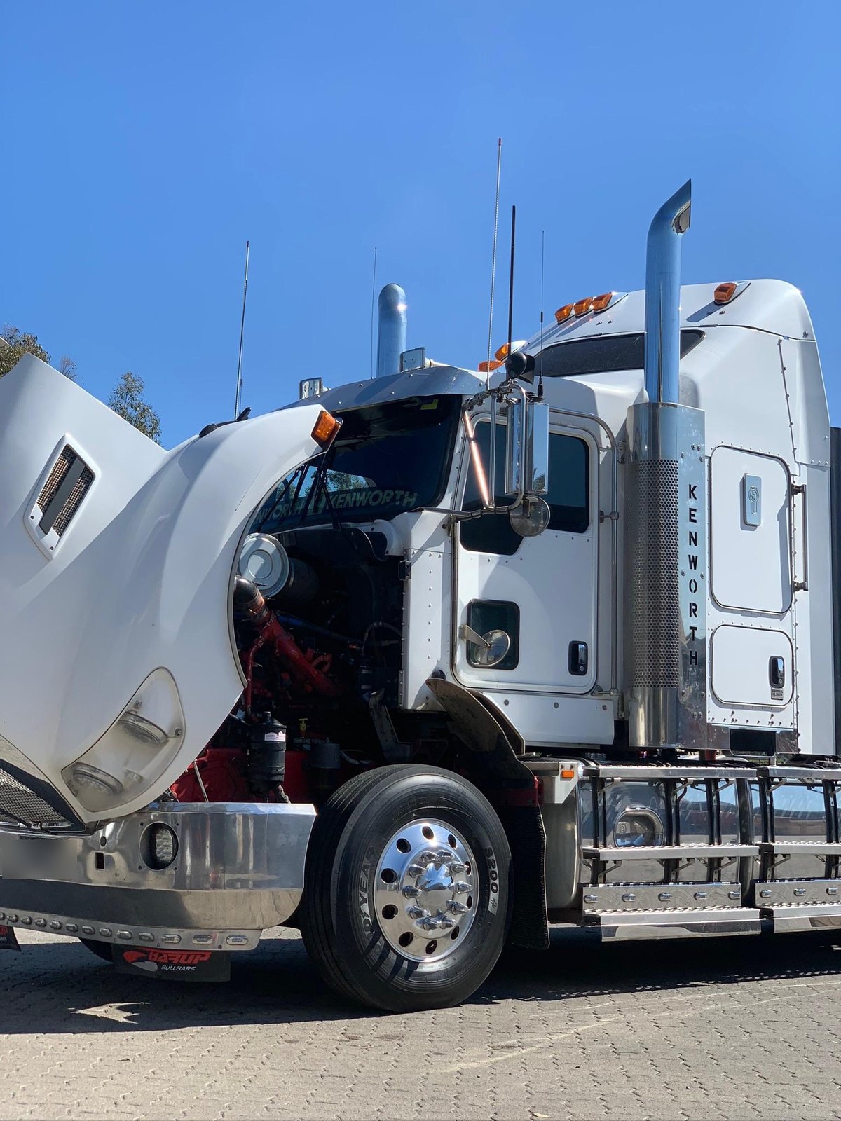 Kenworth with the bonnet up, engine exposed, on site